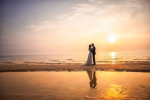 newlyweds on beach at sunset