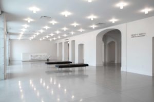 all white room inside museum with 2 black benches
