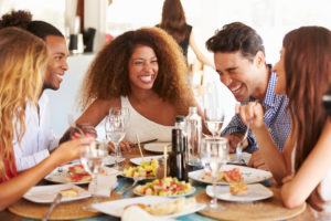 Young group of friends laughing and enjoying lunch