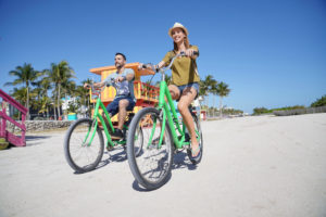 Boy and girl riding green bikes on sand