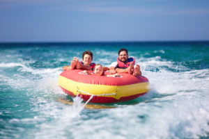 Three siblings in red tube behind boat