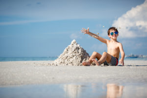 Little boy sitting next to a pile of sand
