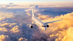Airplane flying above the clouds during golden hour