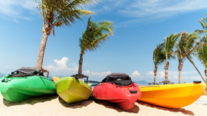 Colorful kayaks sitting in the sand under palm trees