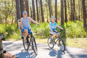 Woman and small boy riding bikes on paved path