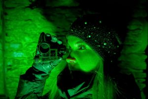 The girl looks through a night vision device in the dark.