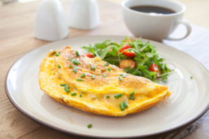 Omelet on a white plate with salad and coffee