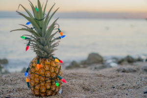 Pineapple wrapped in holiday lights on the beach