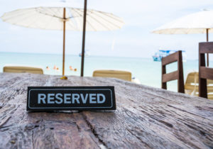 Reserved banner on restaurant table, beach background