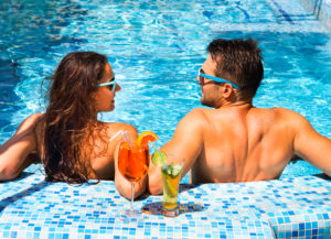 Girl and guy enjoying the pool with drinks