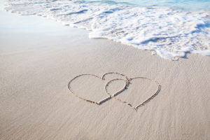 Two hearts drawn in the white sand on the beach