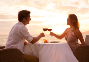 Man and woman drinking wine at sunset near the beach