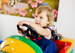 Little girl toddler sitting in clown car at museum