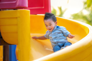 Little boy toddler sliding down yellow slide
