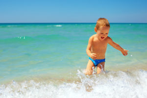 Little boy running in the waves on the beach