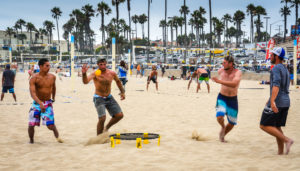 Young men playing a game of Spikeball on the sand