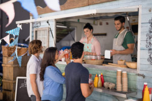 Smiling waiter taking order from customer at counter of food truck