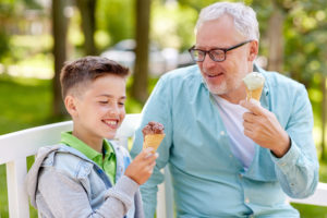 family, generation, communication and people concept - happy grandfather and grandson eating ice cream at summer park