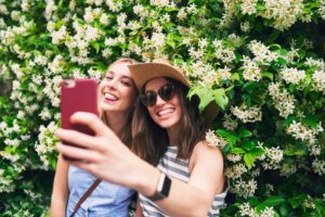 Two friends taking selfies on summer vacation. Girl friends on travel adventure taking photos for social media with smartphone