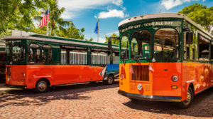 Tourists  travel on historic, orange Trolley Buses of Key West, Florida