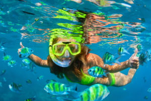 Happy family - girl in snorkeling mask dive with tropical fishes in coral reef sea pool. Travel lifestyle, water sports outdoor adventure, underwater swimming on summer beach holiday with kids.