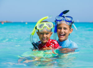 Portrait of happy cute boy and girl wearing snorkeling mask ready to dive in the sea