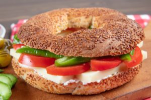 Turkish Bagel Simit Sandwich. Vegan bagel made at home with with cheese, tomato and cucumber on a wooden background. Fast Turkish breakfast