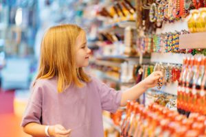 a funny little girl looks with interest at jewelry and souvenirs in the store. sale of goods in the hotel and by the beach in the resort.