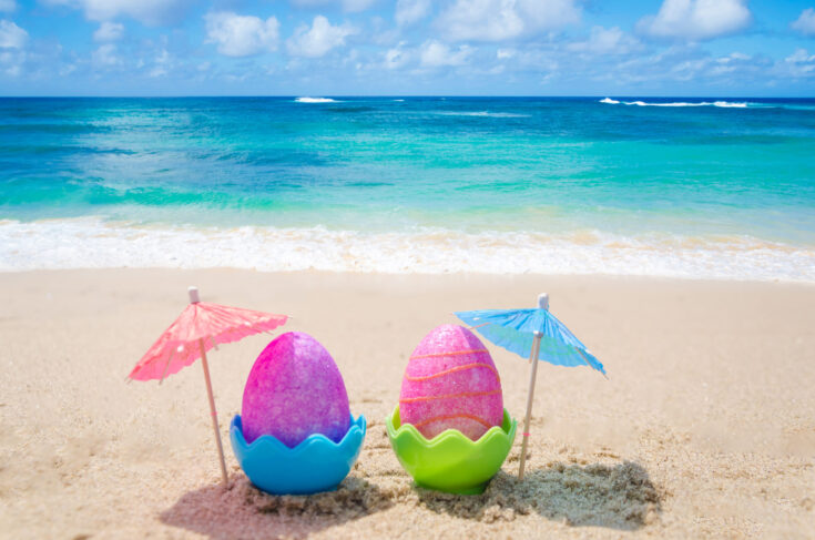 Two,Easter,Eggs,With,Cocktail,Umbrella,On,The,Sandy,Beach