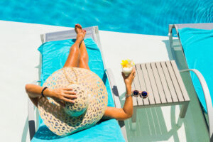 Woman sitting in chair by pool with hat on