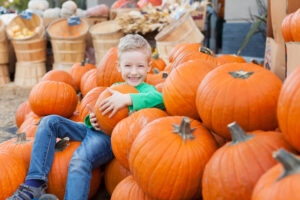 Child sitting among pumpkins